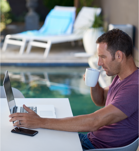 man drinking coffee outside on computer